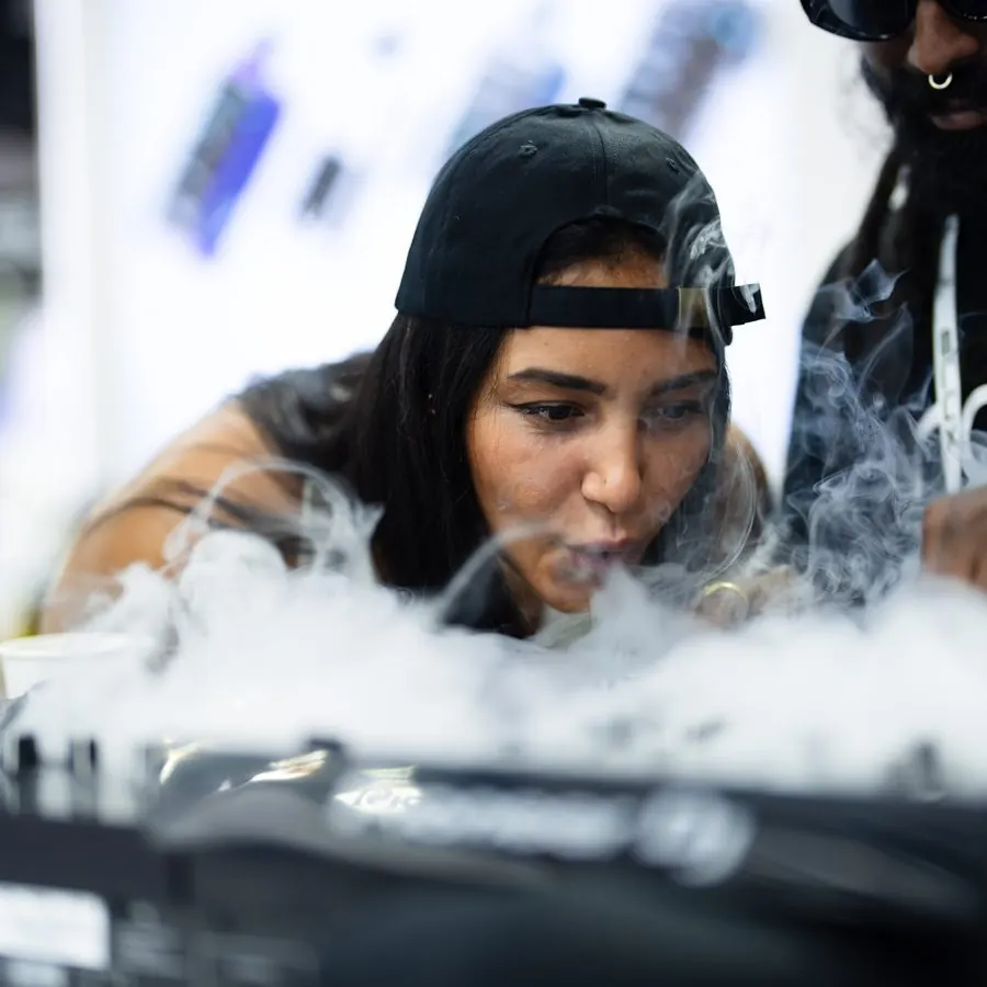 DJ leaning over decks surrounded by fog