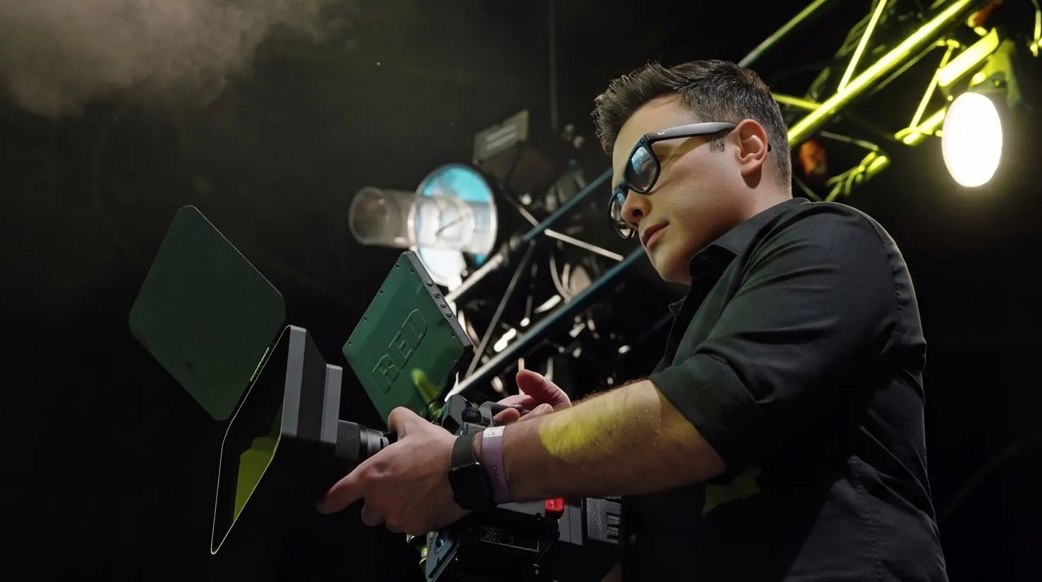 Cinematographer operating a RED camera under stage lights